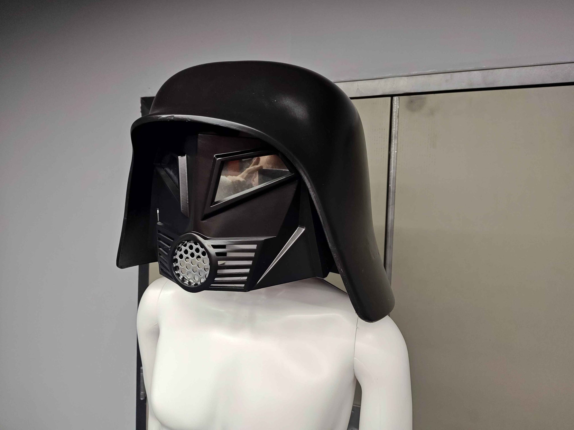 Black helmet with visor on a mannequin against a neutral background